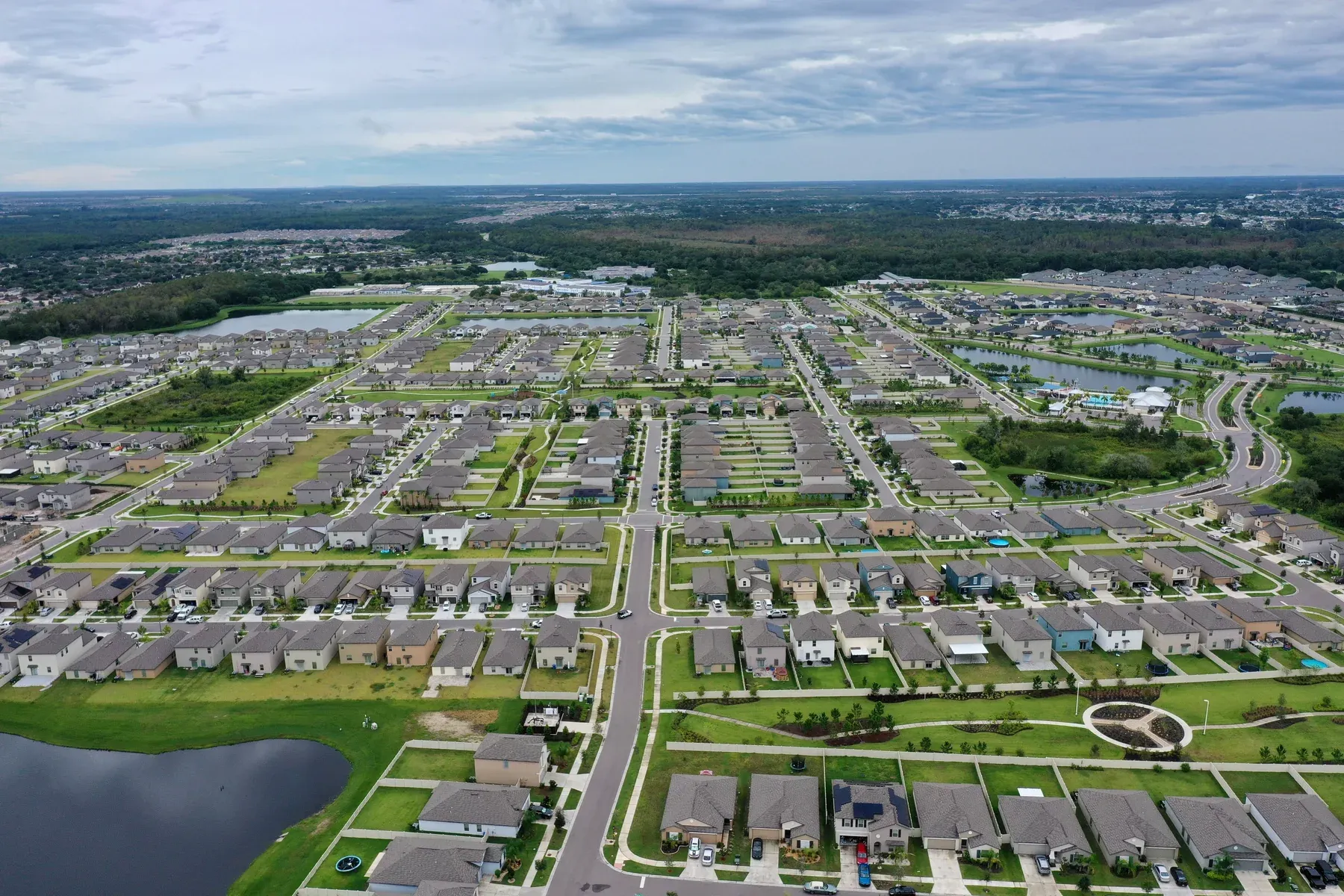 Aerial view of a large suburban subdivision with rows of homes, curving streets and ponds