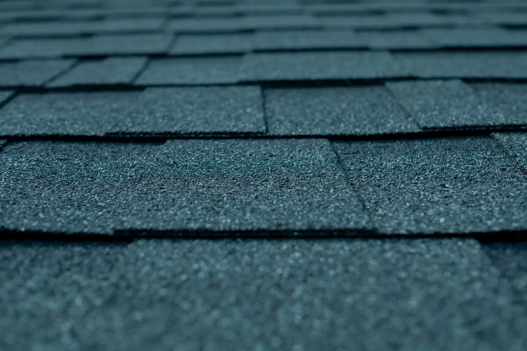 Close-up of blue-gray asphalt shingle courses on a residential roof, shallow depth of field
